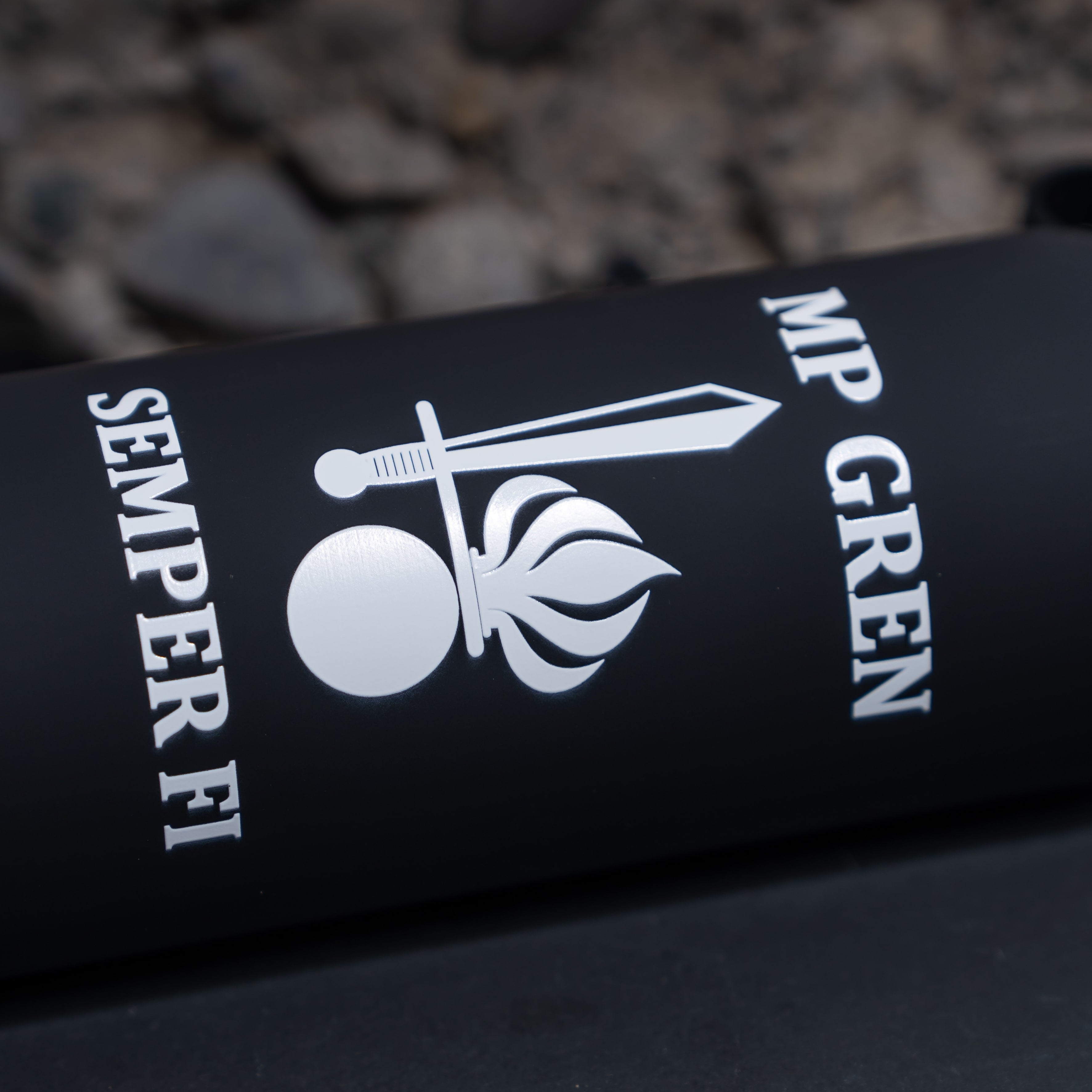 Schwarze Flasche mit Army Coin Ch Logo und "Semper Fi" Schriftzug auf Steinboden.