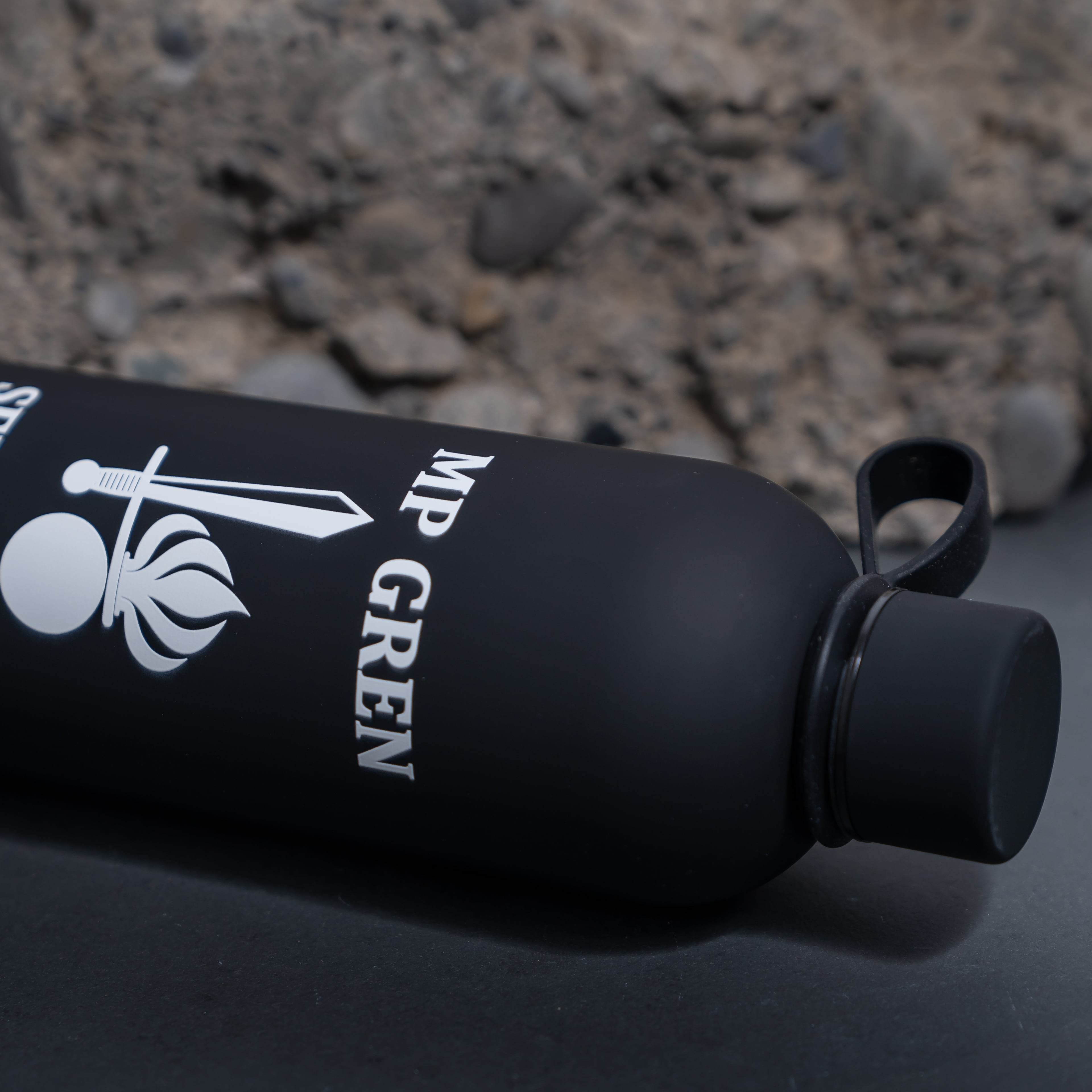 Schwarze Trinkflasche mit Army Coin Ch Logo vor steinigem Hintergrund.