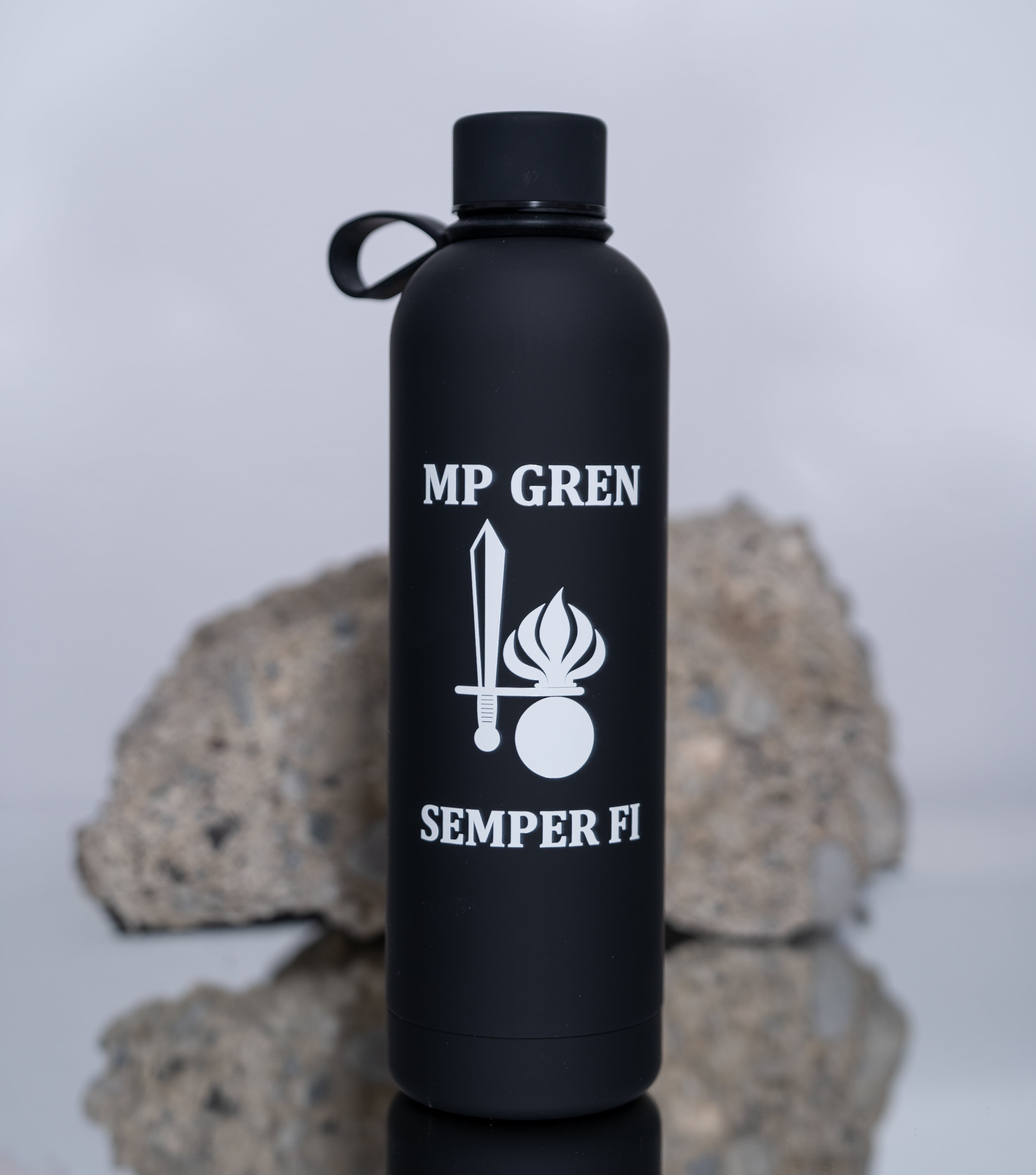Schwarze Trinkflasche mit "MP GREN" und "SEMPER FI" von Army Coin Ch vor Steinen.
