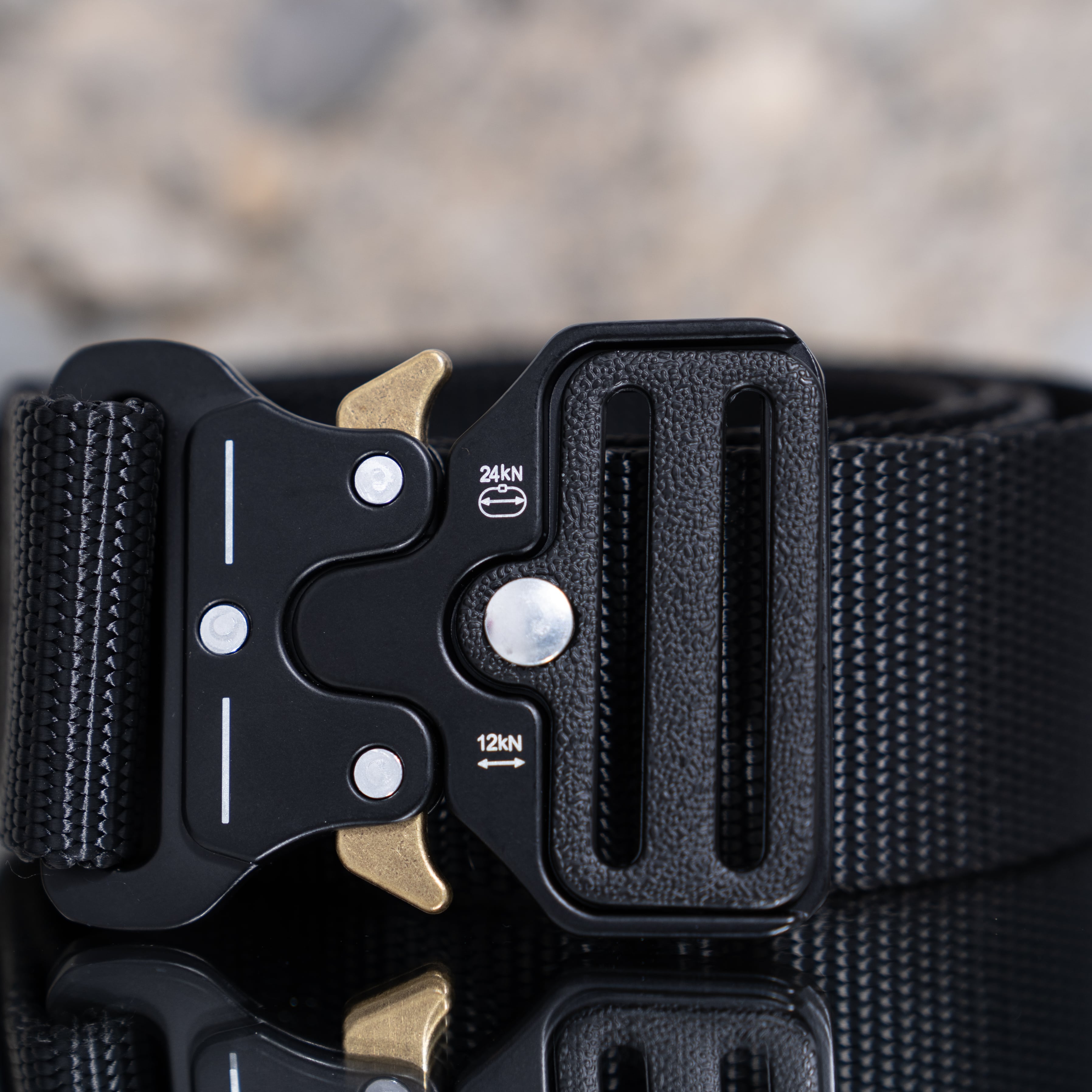 Ein schwarzer Army Coin Ch Gürtel mit robuster Metallschnalle auf reflektierendem Untergrund.